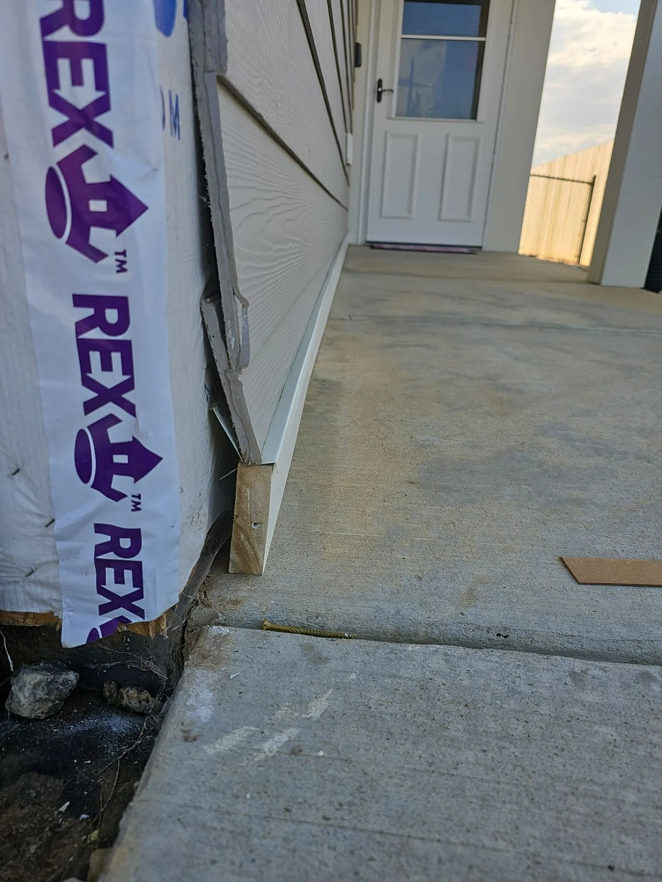 Outside-corner trim at the sidewalk before clearance correction